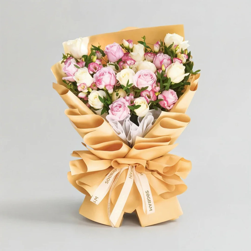 Large bouquet of pink and white roses wrapped in tan paper with decorative ribbon